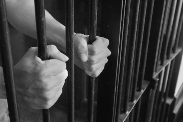 Prison Cell Bars.Hand of the prisoner holding steel lattice jail bars.Criminal justice imprisonment concept. stock photo