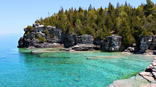 Pristine water of Georgian Bay at one of the most popular Canadian National Parks View of the turquoise clear water and rocky cliff shoreline of the Grotto park near Tobermory Ontario bruce peninsula stock pictures, royalty-free photos & images