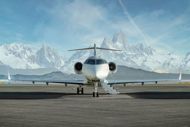 Private Jet waiting on runway Head on photo of a private jet waiting on runway to be boarded with snowy mountains in the background private airplane stock pictures, royalty-free photos & images