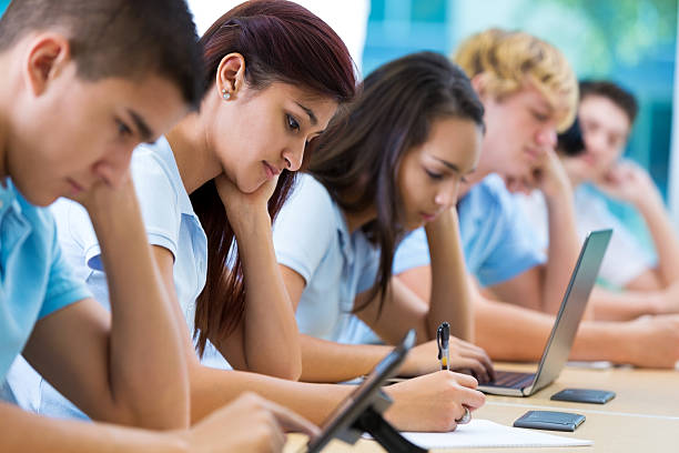 Private school students work in class Row of private high school students work on assignment in class. They are writing or using laptops or digital tablets. They are concentrating as they study. They are wearing school uniforms. universities in texas stock pictures, royalty-free photos & images