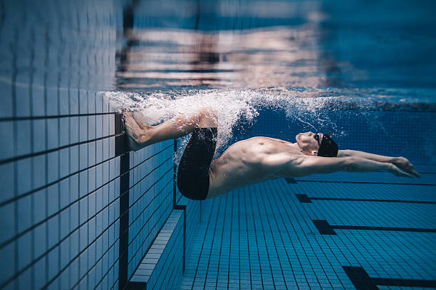 Pro male swimmer in action inside swimming pool Shot of fit young man turning over underwater. Pro male swimmer in action inside swimming pool. jacob ammentorp lund stock pictures, royalty-free photos & images