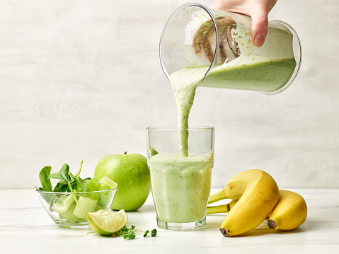 fresh green smoothie pouring into glass ready for healthy breakfast