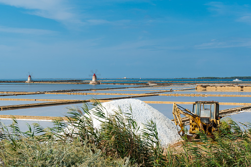 Ancient windmills in the background of this production site of sea salt in the salt evaporation ponds between Trapani and Marsala on Sicily