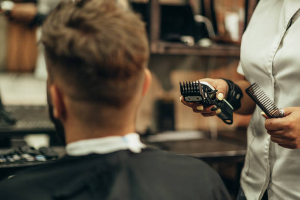 professional barber holding a hair trimmer in her hands - kapper stockfoto's en -beelden