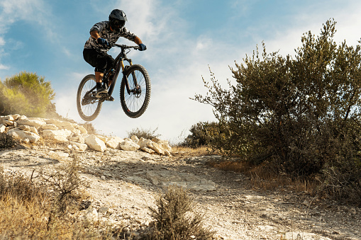 Professional bike rider jumping during downhill ride on his bicycle in mountains
