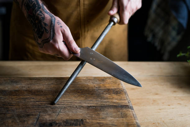 Professional chef sharpening knife in the kitchen Professional chef sharpening knife in the kitchen table knife stock pictures, royalty-free photos & images