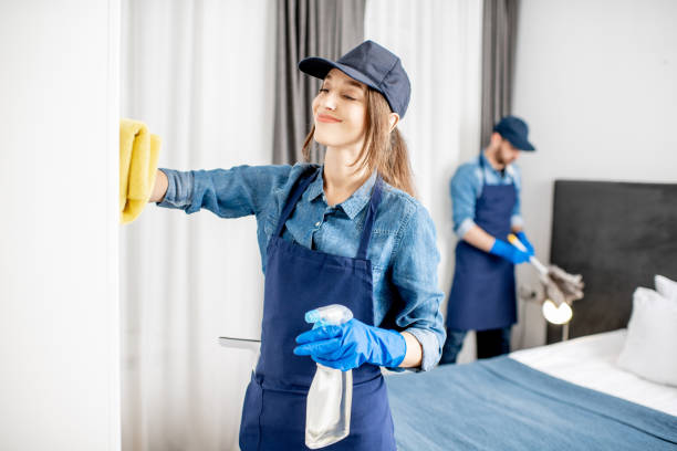 Professional cleaners during the work indoors Couple as a professional cleaners in uniform rubbing furniture and wiping dust in the bedroom or hotel room. Cleaning service concept cleaner stock pictures, royalty-free photos & images