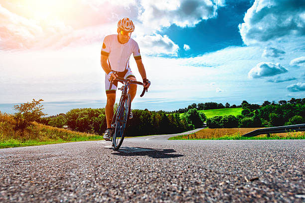 Professional cyclist rides bike with power up a hill stock photo