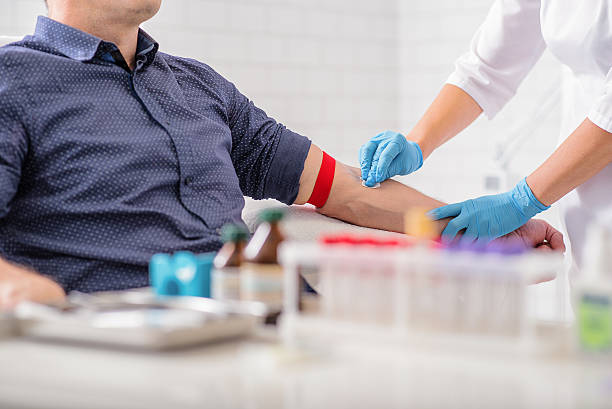 Professional doctor preparing patient for procedure Close up of nurse disinfecting male arm before blood test. Man is sitting on chair near medical set blood stock pictures, royalty-free photos & images