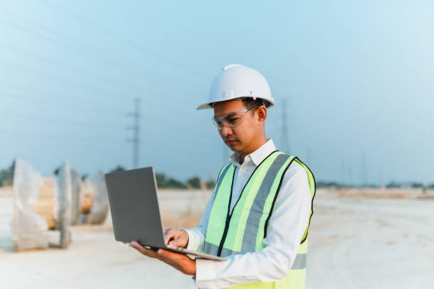 Professional Engineer wearing a helmet inspects a new project in a laptop. stock photo
