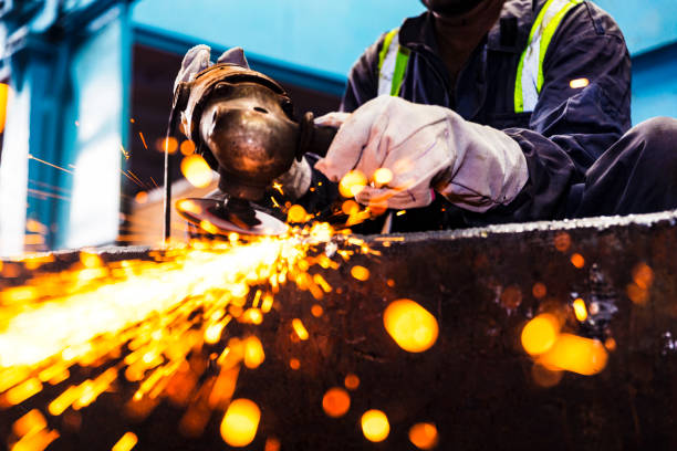 Professional factory employee grinding metals to a polishes finish stock photo