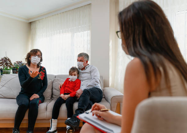 professional female psychologist speaking with client A confident female counselor attentively listens as a patient discusses something during a session. The counselor is wearing a protective mask as she is working during the COVID-19 pandemic. psychologist's help stock pictures, royalty-free photos & images