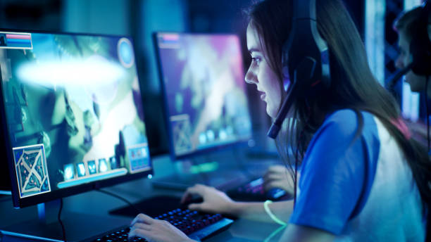 garota profissional jogador joga em mmorpg / jogo de estratégia no seu computador. ela está a participar no torneio de jogos on-line cyber, joga em casa, ou em um internet café. ela usa gaming headset. - gamer - fotografias e filmes do acervo