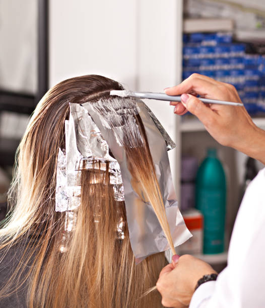 Professional hairdresser dyeing hair of her client. stock photo