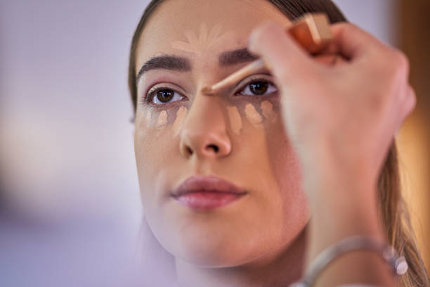 Professional make up artist using a light shade of concealer on a customer to make a nose contour stock photo