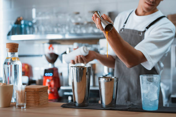 professional male barista making caramel iced frappe while working in local coffee shop stock photo