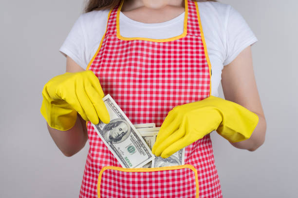 Professional people earn more concept. Cropped close up photo of satisfied happy confident lady putting money into pocket on her red apron isolated grey background Professional people earn more concept. Cropped close up photo of satisfied happy confident lady putting money into pocket on her red apron isolated grey background money in cleaning stock pictures, royalty-free photos & images