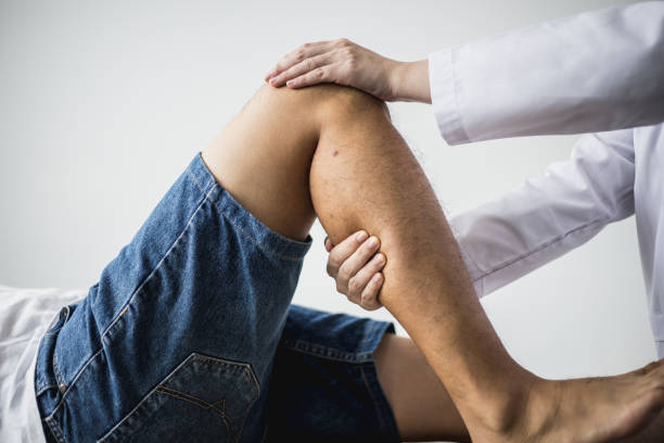A professional physiotherapist is stretching the patient's legs, the patient has muscle dysfunction due to hard work, most often an office worker who has problems sitting for long periods of time. stock photo