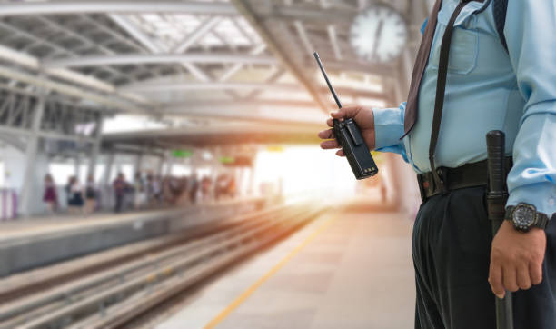 Professional security guard hand holding cb walkie-talkie radio in electric train station, copy space for text. stock photo