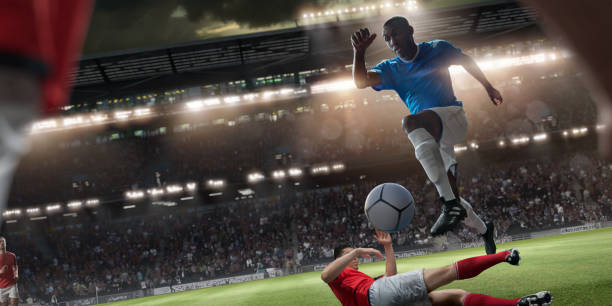 Professional Soccer Player Jumping Over Rival Player During Football Match A view from just behind a footballer of a professional soccer player dressed in generic blue and white football kit, jumping with the ball over a rival player. The action occurs on during an evening soccer game in a generic outdoor floodlit football stadium full of spectators. soccer striker stock pictures, royalty-free photos & images