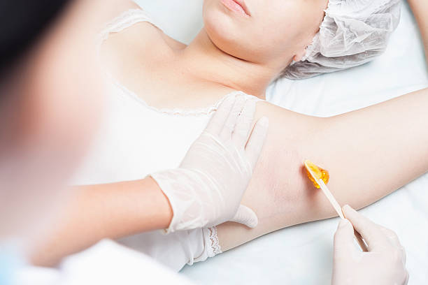 Professional woman at spa doing epilation armpits using sugar stock photo