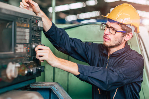 專業青年工人眼鏡，數控機床控制台工程師穿安全服和頭盔在工業工廠工作。 - labor day 個照片及圖片 檔