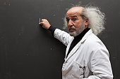 man with a mad hair and a lab coat in front of a blackboard,, holding a piece of chalk
