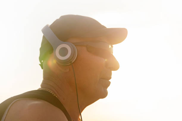 profile of active senior sportsman on a daylight - senior listening music beach bildbanksfoton och bilder