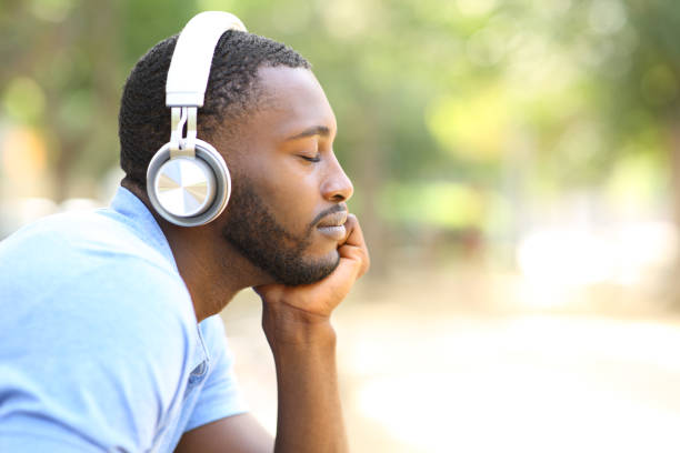 Profile of black man listening to music in a park stock photo