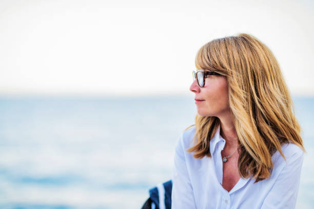 Profile portait of middle aged woman relaxing by the sea stock photo