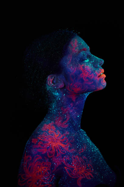 Profile portrait of a beautiful girl alien. Ultraviolet body art blue night sky with stars and pink jellyfish stock photo