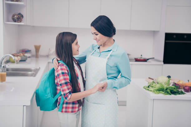 profile side view portrait of two nice-looking lovely sweet adorable attractive cheerful cheery people mature kind careful mum holding hands in light white kitchen interior indoors - foster home bag imagens e fotografias de stock