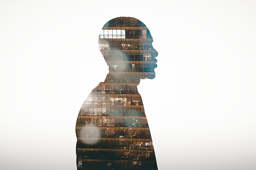 Profile view silhouette of businessman double exposed with city at night