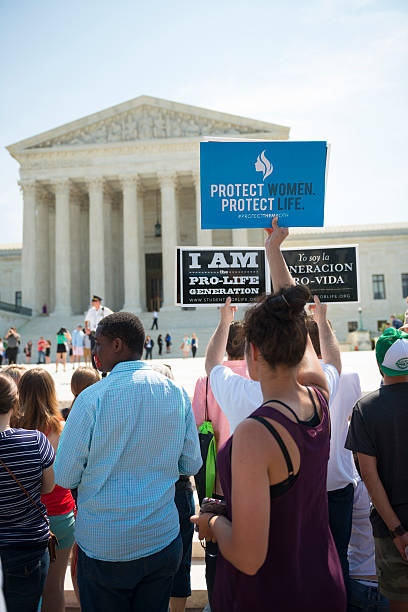 Pro-life supporters with signs outside U.S. Supreme Court Washington DC, USA - June 27, 2016: Pro-life supporters hold signs in front of the U.S. Supreme Court after the court, in a 5-3 ruling in the case Whole Woman's Health v. Hellerstedt, struck down a Texas abortion access law that had been supported by pro-life groups. abortion protest stock pictures, royalty-free photos & images