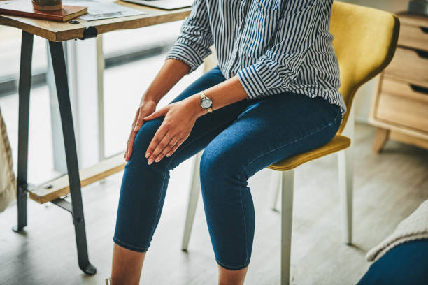 Prolonged periods of sitting can cause stiffness to your joints Closeup shot of an unrecognisable woman rubbing her knee in pain while working from home knee stock pictures, royalty-free photos & images