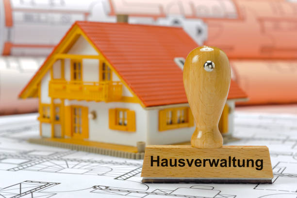 property management printed on rubber stamp standing on plan - in German language: Hausverwaltung stock photo