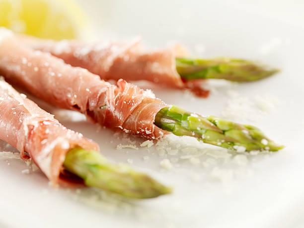 Prosciutto Wrapped Asparagus Prosciutto Wrapped Asparagus with Freshly Grated Cheese -Photographed on Hasselblad H3D2-39mb Camera prosciutto stock pictures, royalty-free photos & images