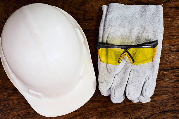 Protective equipments. A pair of gloves, protective goggles and a helmet, on a wooden surface. It suggests construction and industry. individual event stock pictures, royalty-free photos & images