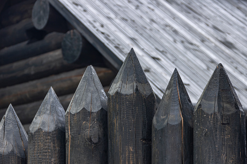 A protective fence made of logs with sharp upper ends, used in ancient Russia to protect against enemies. Traditional old Russian wooden construction of houses.
