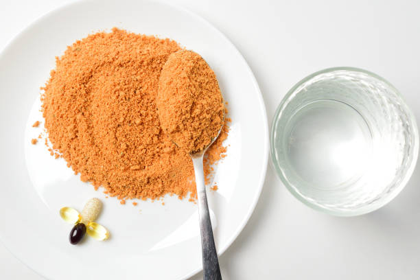 Protein soup powder on a plate. Tomato protein soup powder on a spoon. Meal replacement. Dry soup. Multivitamins, astaxanthin, fish oil, omega pills on a plate.  Closeup. pea protein powder stock pictures, royalty-free photos & images