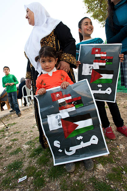 Protest in Palestine "Nabi Samuel, Occupied Palestinian Territories - April 1, 2011: Palestinian children hold signs with the flags of Tunisia, Egypt, Libya, Yemen, and Palestine with the question in Arabic: ""When"" at an olive planting event in observance of Land Day 2011." tunisian girls stock pictures, royalty-free photos & images