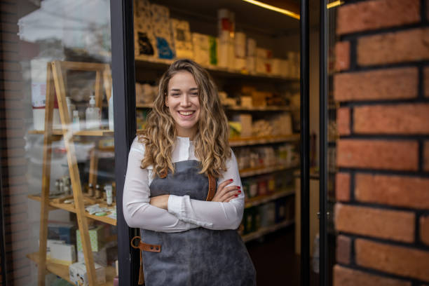 Proud and joyful female small business owner in front of the store stock photo