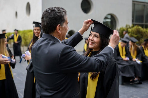 Proud father arranging the mortarboar of her graduating daughter stock photo