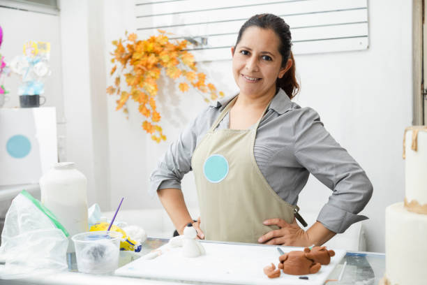 Proud latin woman in her pastry shop - woman with apron watching the camera in her cake workshop - enterprising Hispanic woman woman with apron watching the camera in her cake workshop columbian woman stock pictures, royalty-free photos & images