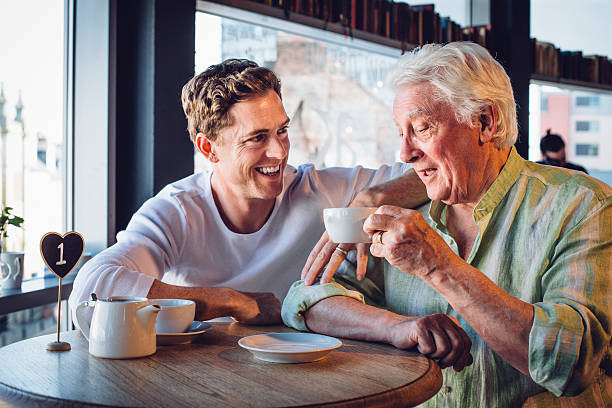 proud son enjoying a coffee with his mature dad - coffee shop old stock pictures, royalty-free photos & images