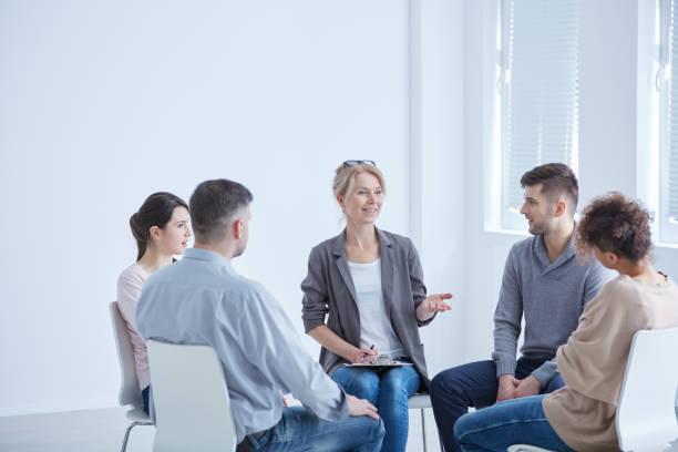 Psychotherapist and group Female psychotherapist talking with her group during session group therapy stock pictures, royalty-free photos & images
