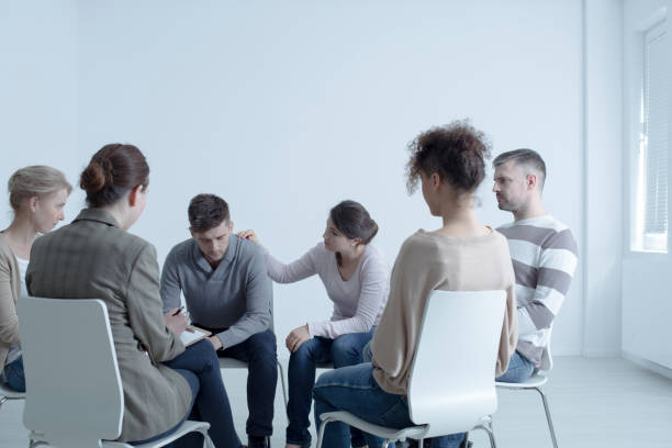 Psychotherapist comforting man Psychotherapist comforting man with depression during psychotherapy meeting drug abuse stock pictures, royalty-free photos & images