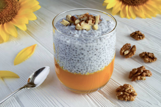 Pudding with chiaseed, pumpkin  and walnuts in the drinking glass  on the white  wooden background. Close-up. stock photo