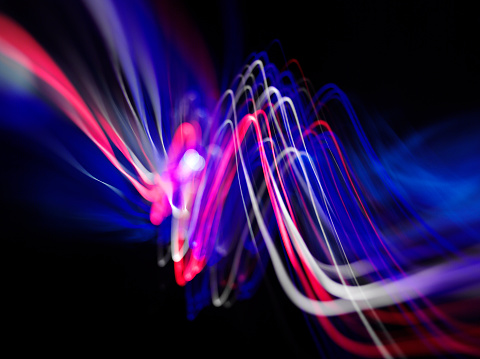 Waves of coloured lights with copy space on a dark background.