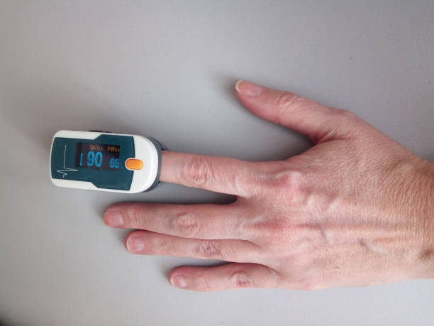 pulse oximeter on a finger in a mature woman, measurement of oxygen level in the blood, - cor saturada imagens e fotografias de stock